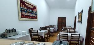 a dining room with tables and chairs and a picture on the wall at Royal-inn SPA & Pousada in Itanhaém