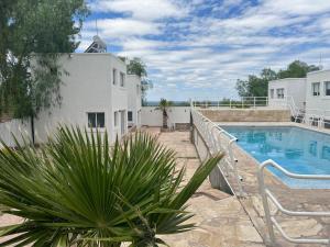 a swimming pool next to a white building and a house at Cerro Arco Apart Hotel in El Challao