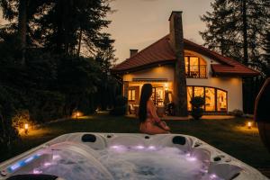 a woman sitting next to a hot tub in front of a house at Zarabie Residence in Myślenice