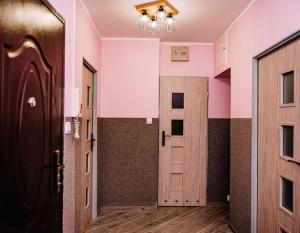 a hallway with a door in a room with pink walls at Apartament blisko Czarnej Góry in Stronie Śląskie