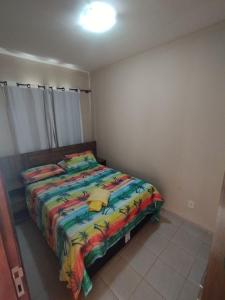 a bedroom with a bed with a colorful comforter at Chalet no paraíso in Maracajaú