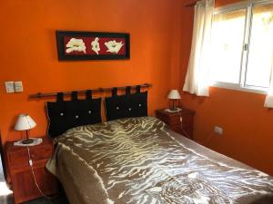 a bedroom with an orange wall with a bed at Cabaña Hakuna Matata in Santa Rosa de Calamuchita