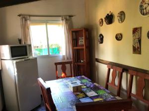 a kitchen with a table with a microwave and a refrigerator at Cabaña Hakuna Matata in Santa Rosa de Calamuchita