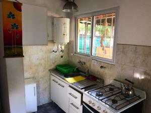 cocina con fogones, fregadero y ventana en Cabaña Hakuna Matata en Santa Rosa de Calamuchita