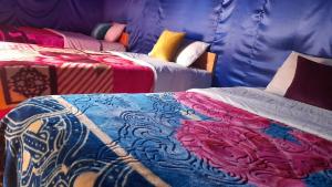 a room with two beds with colorful blankets and pillows at Oasis enchantée in Merzouga