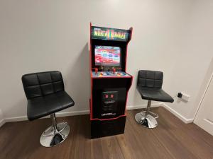 a video game machine with two chairs in a room at Numero Uno Detached Aparthouse in Newcastle upon Tyne