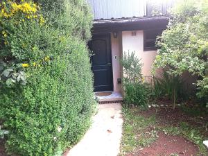 uma casa com uma porta preta e alguns arbustos em Cabañas Los Nonos em El Bolsón