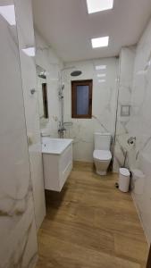 a white bathroom with a sink and a toilet at Guest House Gogemi in Bansko