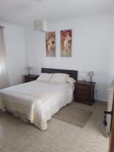 1 dormitorio con 1 cama blanca y 2 mesitas de noche en Agradable casa con piscina en la serranía. en Arriate