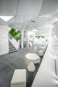 una sala d'attesa con tavoli bianchi e panche bianche di Optimi Rooms Madrid a Madrid