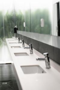 una fila de lavabos en un baño con espejos en Optimi Rooms Madrid, en Madrid