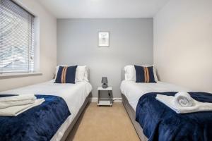 1 dormitorio con 2 camas con sábanas azules y blancas en Comfortable House close to Junction 15 of M1 en Northampton