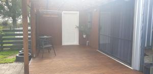 eine Veranda mit einer weißen Tür und einer Holzterrasse in der Unterkunft Rural in the city in Palmerston North
