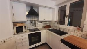 a kitchen with white cabinets and a black sink at Lovely 3 Bedroom Apt. in Maloja