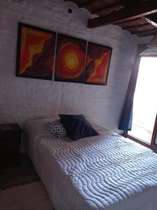 1 cama en un dormitorio con pinturas en la pared en Hermosa casa con parque en Córdoba