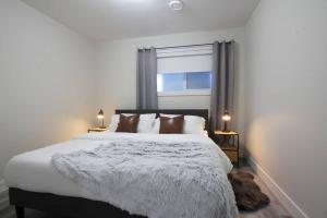 1 dormitorio con 1 cama blanca grande y ventana en Executive Bsmt Suite, King Bed, 5 min to DT & Whyte Ave, Sleeps 6! en Edmonton