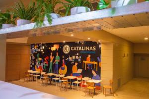 a room with tables and chairs and a wall with a mural at Hotel Catalinas Tucuman in San Miguel de Tucumán