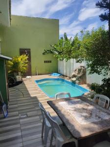 un patio trasero con piscina, mesa y sillas en Casa Samauma Aluguel de Quartos en Florianópolis