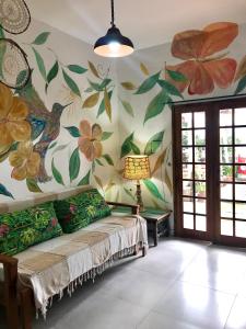 a living room with a couch and flowers on the wall at Amarelo Hibisco in Guarda do Embaú