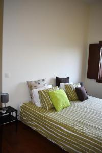 um quarto com uma cama com almofadas verdes e brancas em O Cantinho Alentejano em Cuba