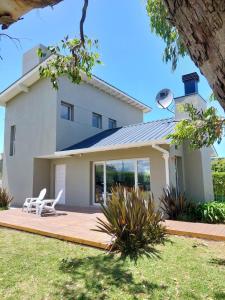 Casa blanca con patio con 2 sillas blancas en Casa Mar Chiquita en Balneario Mar Chiquita