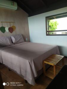 a bedroom with a large bed and a window at Vila Artesania in Bombinhas