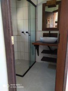 a bathroom with a sink and a glass shower at Vila Artesania in Bombinhas