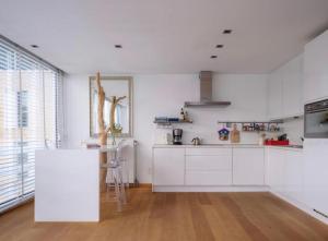 a kitchen with white cabinets and a wooden floor at Designloft in Ghent