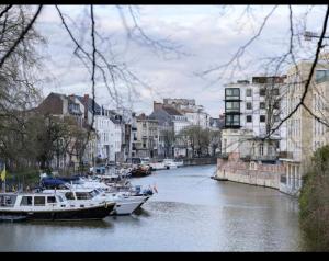 two boats are docked on a river in a city at Designloft in Ghent