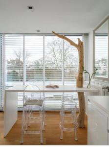 a white kitchen with a table and chairs and a tree at Designloft in Ghent