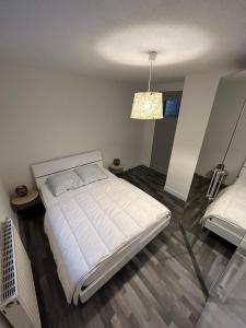 - une chambre avec un lit blanc et un lustre dans l'établissement Appartement de Camargaux 70m2 secteur très calme, à La Bresse