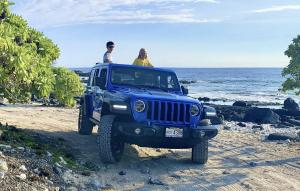 two people sitting in a blue jeep on a beach at Luxe Designer Home, Best 180 Ocean View, Hot Tub & Pool estate in Papa Bay Estates