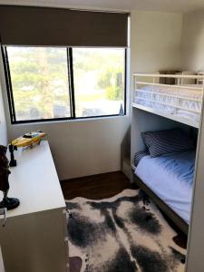 a bedroom with a bunk bed with a desk and a window at Manly family executive apartment in Sydney