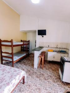 a room with a bunk bed and a kitchen at Diva Surf Quartos in Ubatuba