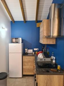 een keuken met een witte koelkast en een blauwe muur bij Bung-hello Village,Petit Bungalow confortable avec jacuzzi in Trois-Rivières
