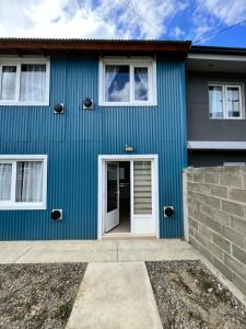 una casa azul con una puerta blanca en Bahía Golondrina en Ushuaia