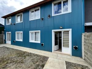 une maison bleue avec des fenêtres blanches dans l'établissement Bahía Golondrina, à Ushuaia