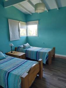 2 camas en una habitación con paredes azules en Casa Mar Chiquita en Balneario Mar Chiquita