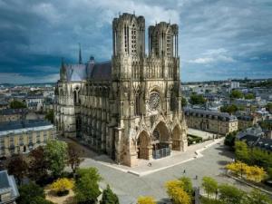 eine alte Kathedrale mit einer Stadt im Hintergrund in der Unterkunft Appartement lumineux proche Cathédrale in Reims