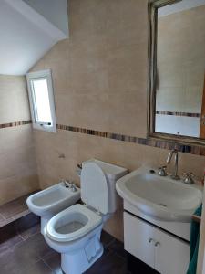 a bathroom with a toilet and a sink and a mirror at Casa Mar Chiquita in Balneario Mar Chiquita