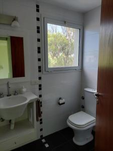 baño con lavabo y aseo y ventana en Casa Mar Chiquita en Balneario Mar Chiquita