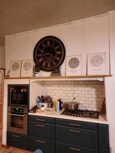 a kitchen with a clock on the wall above a stove at Chambre d'hôtes Le Relais de Belloy in Belloy sur Somme