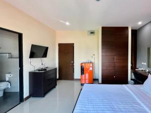 a hotel room with a bed and a television and a bathroom at Ma Chic & Cozy in Lampang