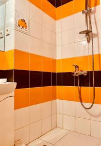 リヴィウにあるFavorit Apartomentのオレンジと白のタイルを使用したバスルーム(シャワー付)