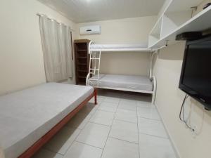 a small room with two beds and a flat screen tv at Kitnets Recanto Caiobá in Matinhos