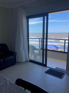 um quarto com uma cama e vista para o oceano em APARTAMENTO BEIRA MAR EM BALNEÁRIO PEREQUÊ em Porto Belo