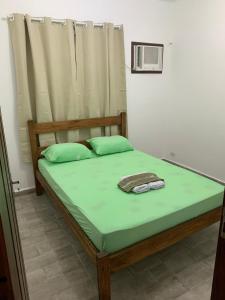 a bedroom with a bed with green sheets and a window at Quarto com entrada independente in Paraty