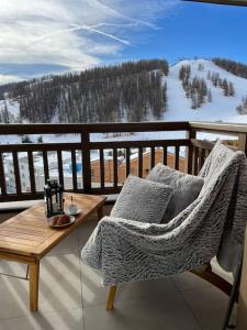 una silla y una mesa en un balcón con vistas en Résidence Valberg L'Horizon, en Péone