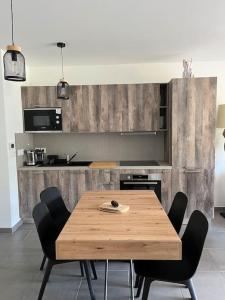 a kitchen with a wooden table and black chairs at Résidence Valberg L'Horizon in Péone