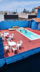 a pool with tables and chairs and people in it at Pousada Portal da Praia in Capão da Canoa